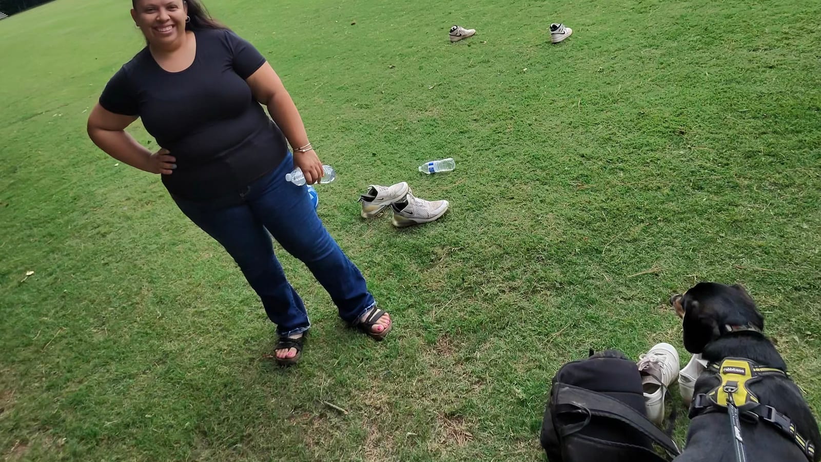 Sofia at a soccer field, with cleats, water bottles and a bag on the grass beside her